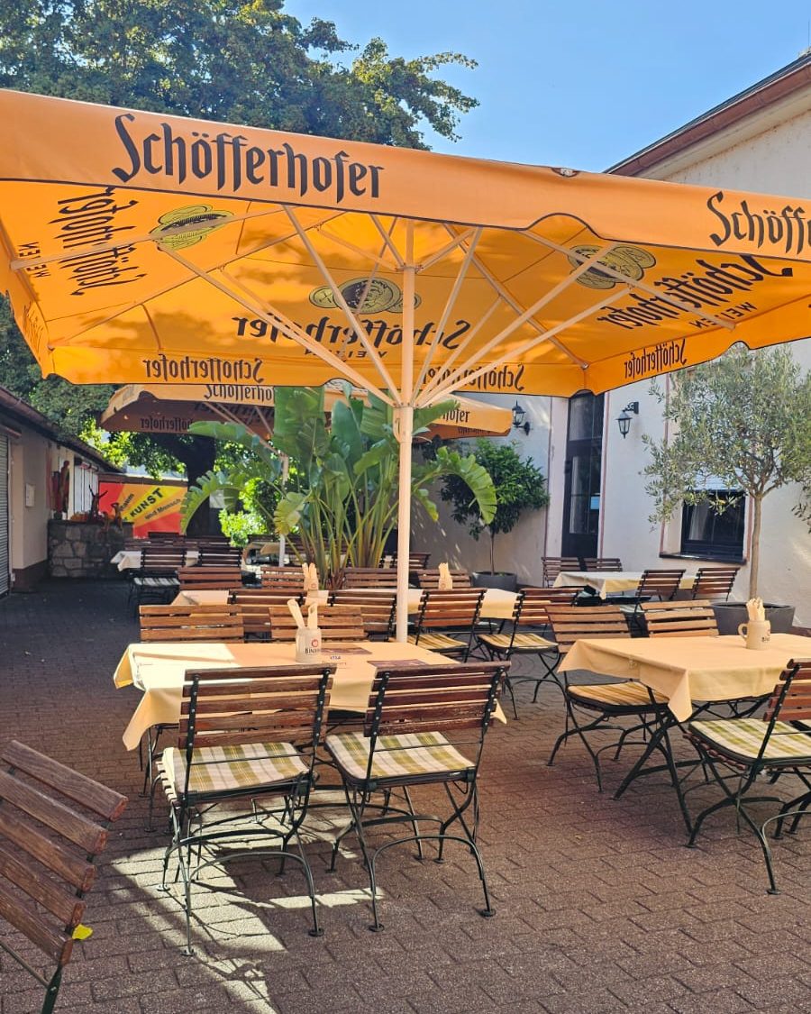 Tische und Stühle unter orangefarbenen Sonnenschirmen