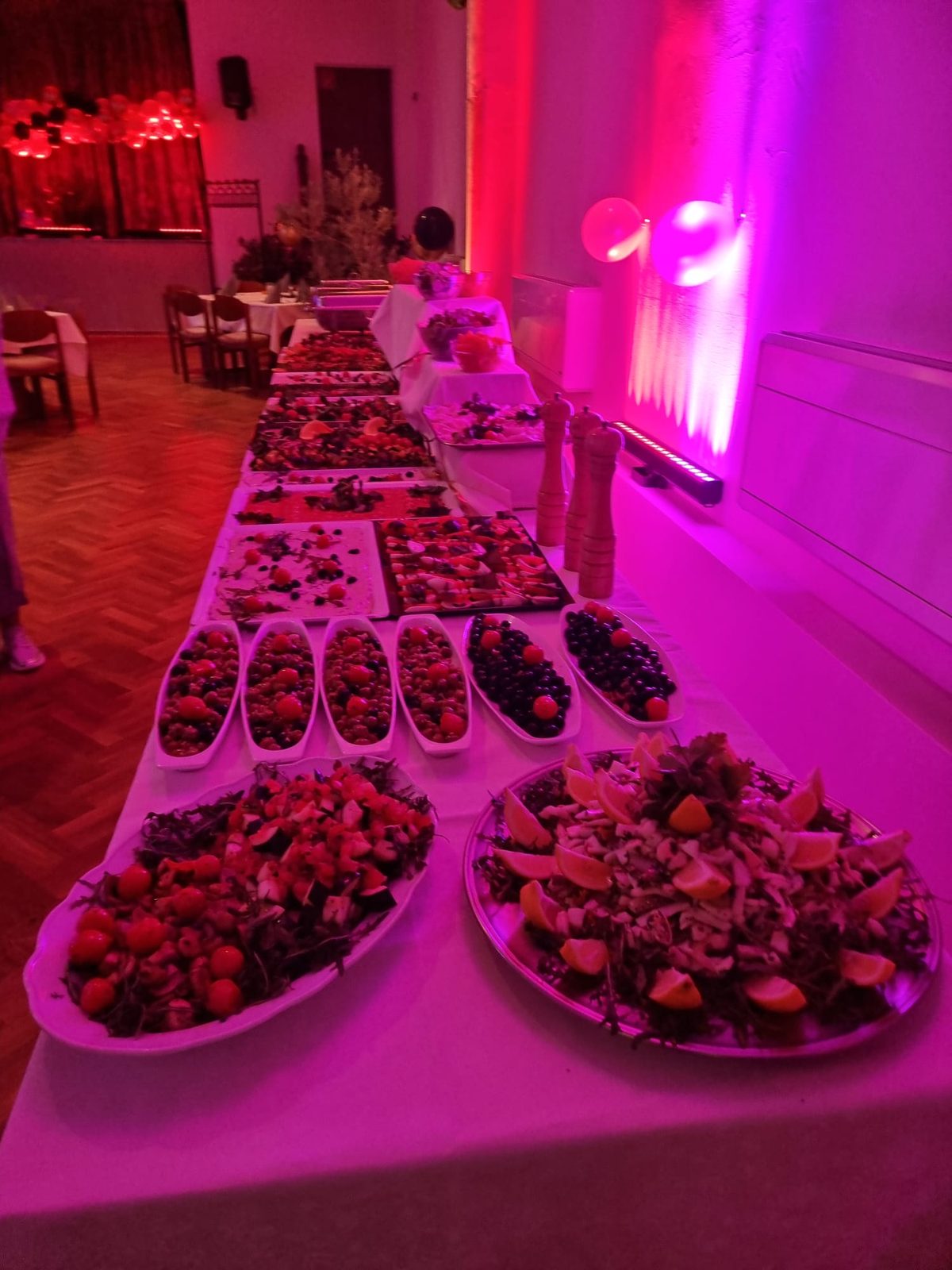 Buffet mit Salaten und Vorspeisen unter rotem Festlicht